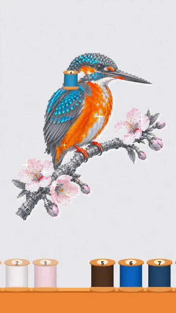 A kingfisher on a cherry branch, half stitched in the app, with a row of numbered thread spools below